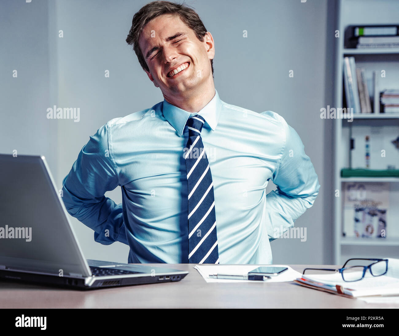 Dipendente soffre di grave dolore nel retro. Foto di un uomo lavora in ufficio. Concetto medico. Foto Stock