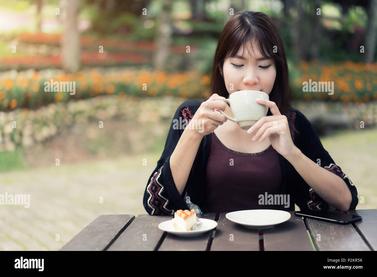 Donne asiatiche rilassante nel giardino di casa con la tazza di caffè e la sensazione di refresh. Foto Stock