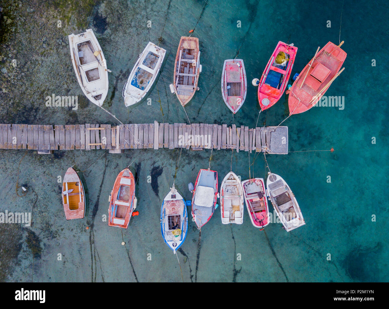 Una vista dall'alto di colorate barche da pesca di ancoraggio nel marina vicino al molo molo in legno, Grecia Foto Stock