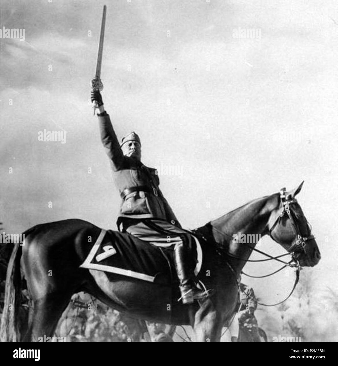 . Italiano: Benito Mussolini alle porte di Tripoli (Libia) innalza la 'spada dell'Islam' la cui elsa è in oro massiccio, e si proclama "protettore dell'Islam", prima di entrare in città alla testa di 2600 cavalieri . Il 20 marzo 1937. Unknown 59 Mussolini spada islam Foto Stock