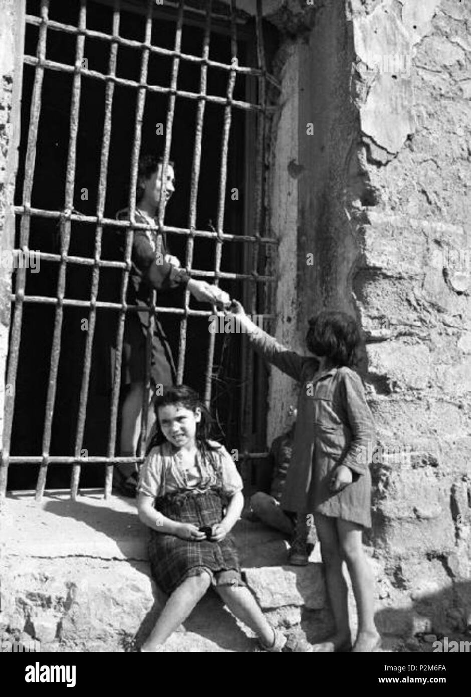 . Inglese: Napoli, Italia 1946: donna e bambini . Il 13 maggio 1946. Federico Patellani 59 Napoli - Edificio semi distrutto dai bombardamenti - ingresso chiuso da una grata - donna e bambini, 1946 (Napoli, Italia, dopo la II Guerra Mondiale, la donna e i bambini) Foto Stock