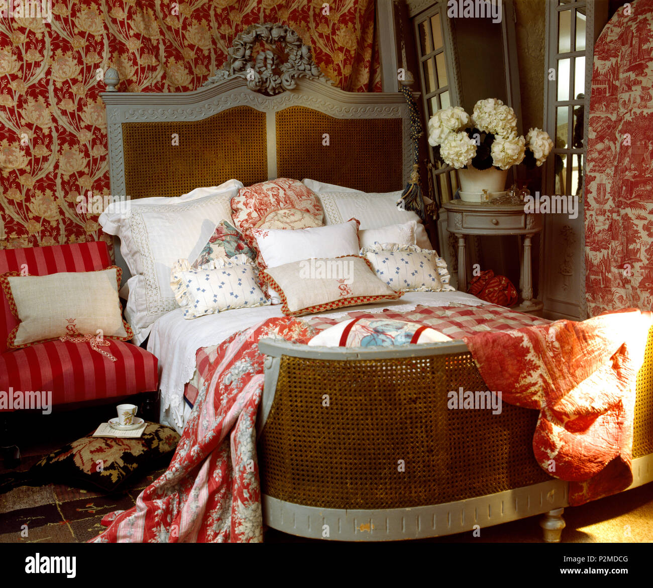 Rosso modellato gettare sul francese antico impilati a letto con cuscini e  guanciali in paese camera da letto con uno sfondo rosso Foto stock - Alamy
