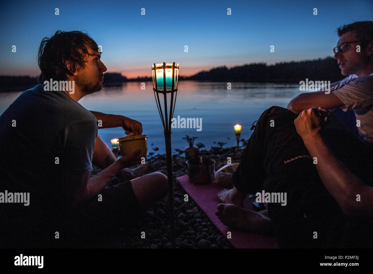 Tre giovani uomini seduti su un lago di notte, Freilassing, Baviera, Germania Foto Stock