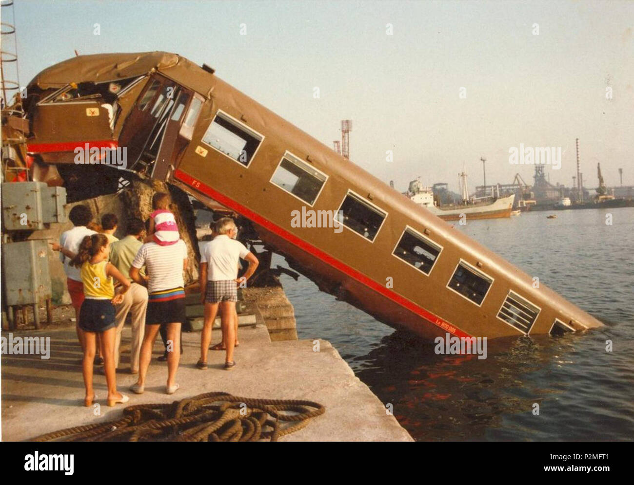 . Italiano: Incidente ferroviario al porto di Piombino del 31 luglio 1983: il convoglio 'Freccia dell'Elba' in marcia verso la stazione di Piombino Marittima, nell'approssimarsi a quest'ultima non riesce ad attuare correttamente le operazioni di frenatura, impatta col terminale postero sul molo al termine dei binari, lo abbatte e concludere la propria corsa in mare. L'elettromotrice di testa ALe 840 ne risultò completamente immersa, seguita dalla rimorchiata le 800.005 che si immergono anch'essa parzialmente in acqua, rimanendo in bilico sul bordo del molo; il resto del convoglio, composto da ONU'al Foto Stock