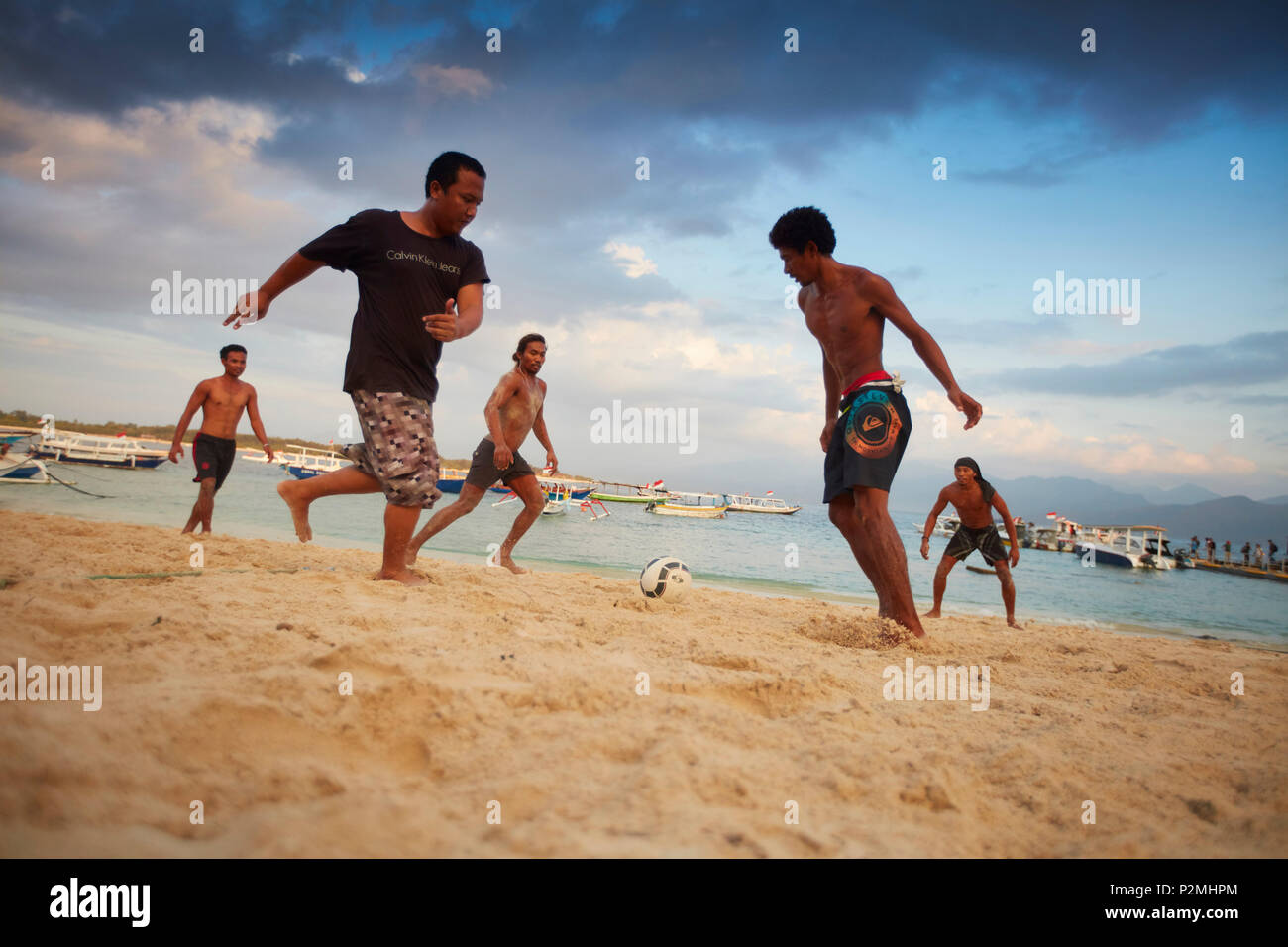I giovani locali che giocano a calcio sulla spiaggia Trawangan, Gili Trawangan, Lombok, Indonesia Foto Stock