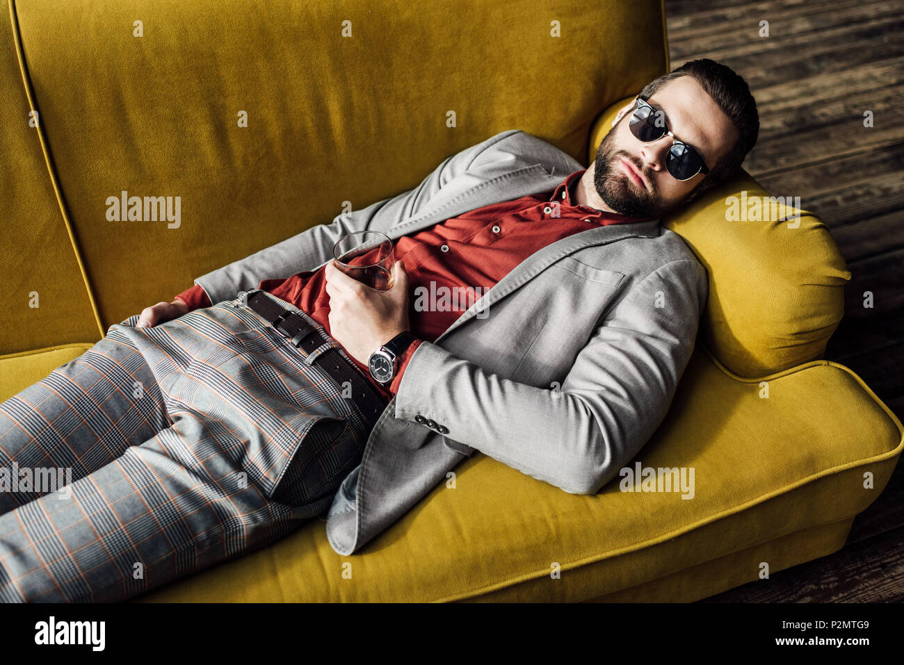 Uomo ubriaco in occhiali da sole con un bicchiere di cognac che dorme sul  divano Foto stock - Alamy