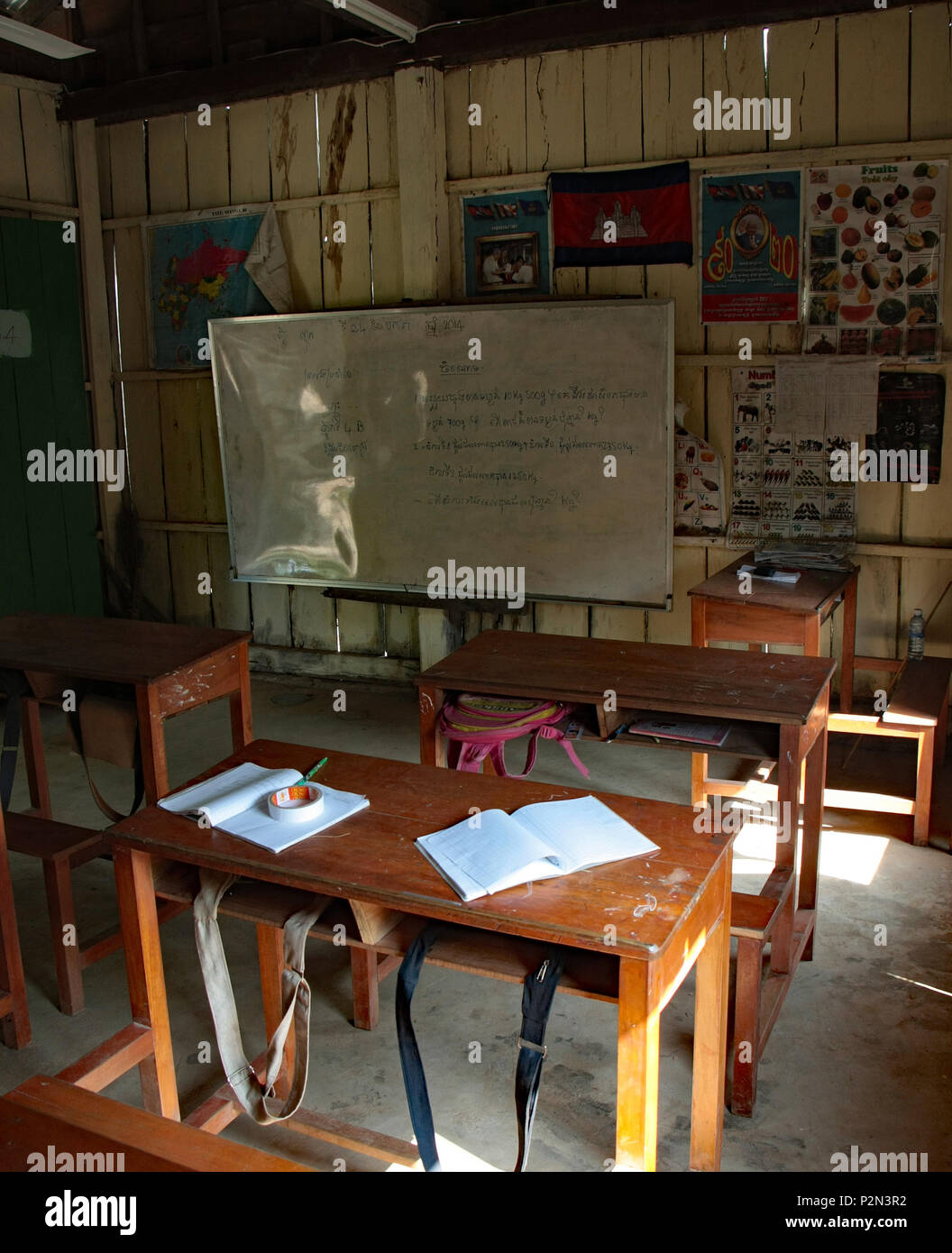 Una scuola rurale classe a risma in Sihanouk provincia. Mostra scrivanie di legno, una lavagna bianca, quaderni, in Cambogia la bandiera e dei poster. Foto Stock