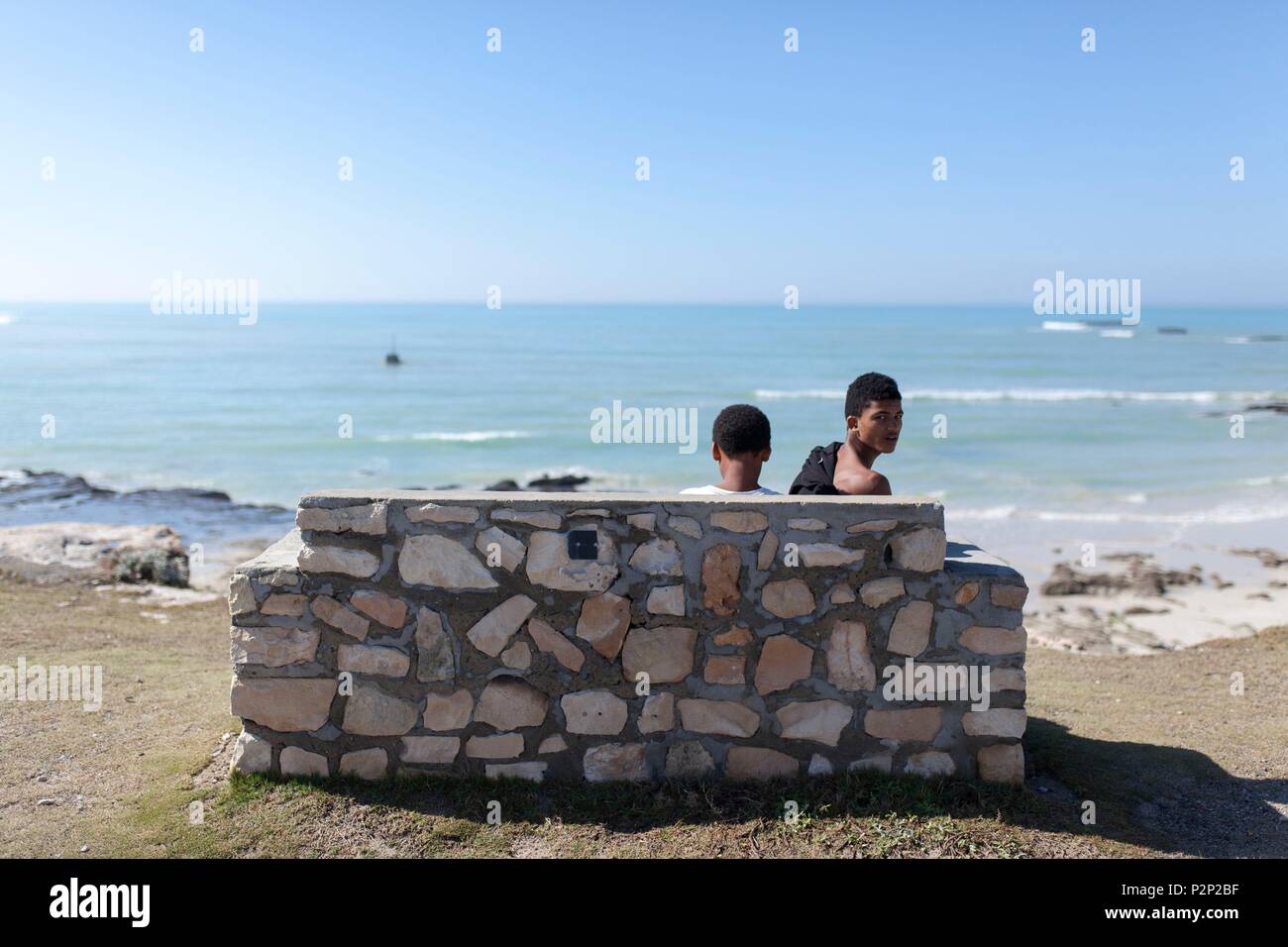 Sud Africa, Western Cape, villaggio dei giovani seduta su una panchina sopra Arniston Beach Foto Stock