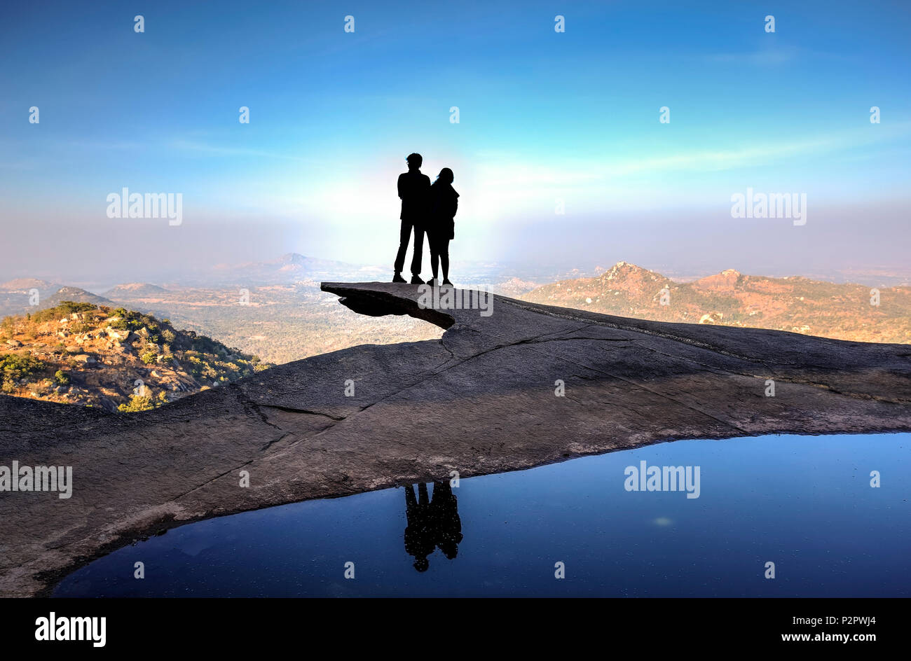 Giovane silhouette in piedi sul bordo di una scogliera con le loro riflessioni sull'acqua Foto Stock