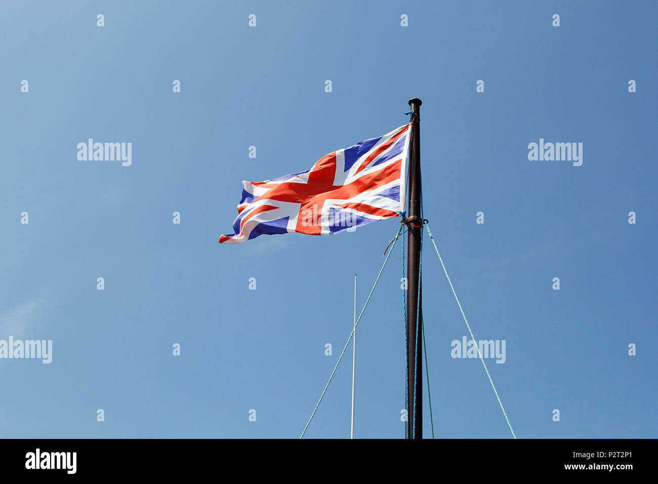 Union Jack flag battenti in la brezza contro un cielo blu sullo sfondo. Foto Stock