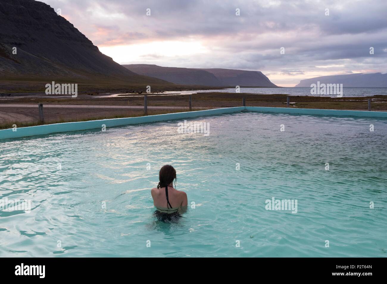 L'Islanda, a ovest di fiordi, Bildudalur, Reykjarfjordur, donna in una piscina geotermica al fondo del fiordo di Arnarfjordur Foto Stock
