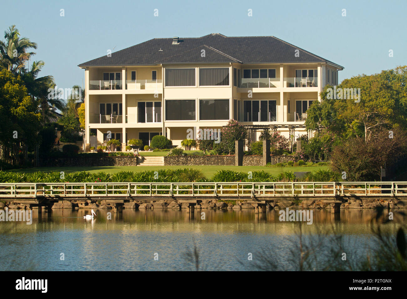 Moderno albergo a tre piani di palazzo in mattoni con prati e giardini a fianco di acque blu del lago e sotto il cielo blu a Bundaberg Queensland Australia Foto Stock