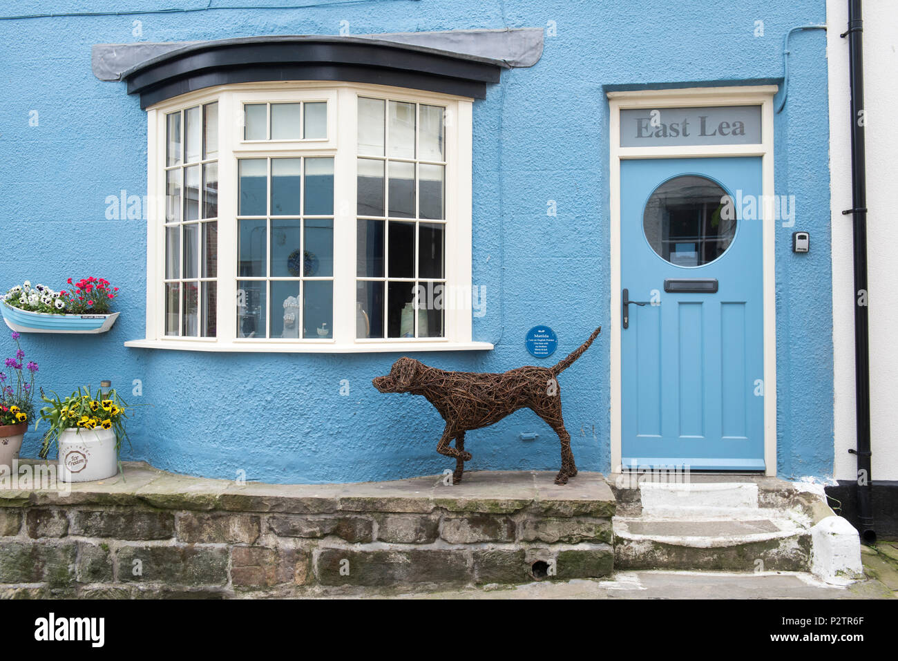 Cane di vimini al di fuori di un edificio sulla Strada Alta nel villaggio di Staithes, North Yorkshire England Regno Unito Foto Stock