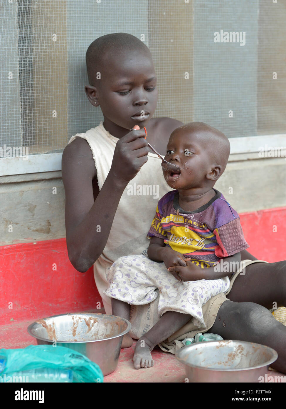 Una ragazza alimenta i suoi gemelli in un supplementare programma alimentare per i bambini malnutriti e madri gestito dalla scuola di Loreto a Rumbek, sud Sudan Foto Stock