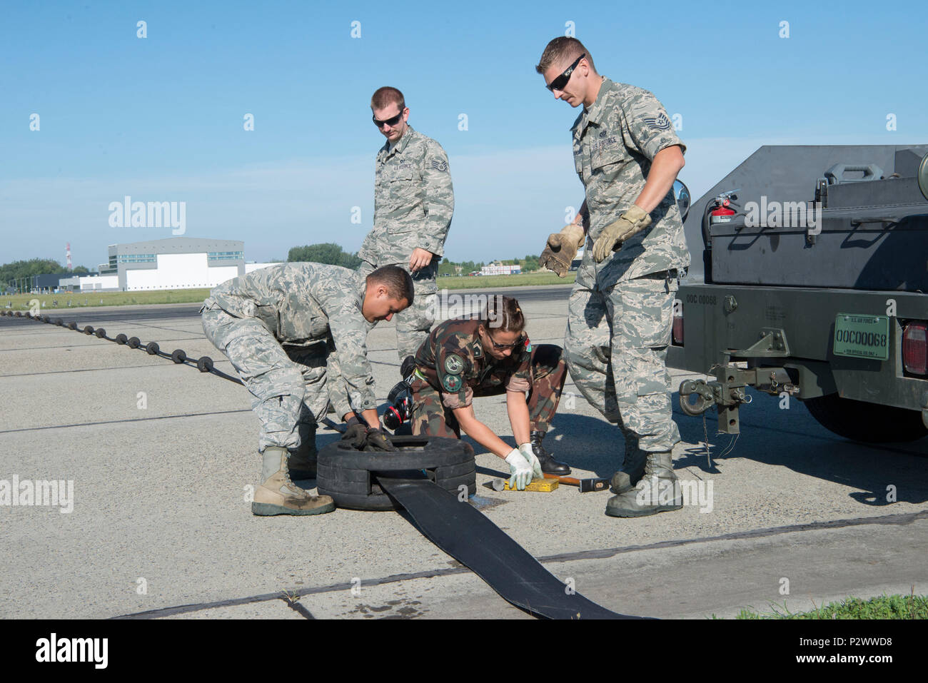 Stati Uniti Senior Airman Mitch Martinez, Staff Sgt. Matteo Wallenburg e Tech. Sgt. Alex Atkins, la produzione elettrica da personale del centoquarantesimo ala, Colorado Air National Guard lavorare con Hungarian Air Force Sergeant (Ormester) Szabone Orovecz Ildiko, anche un potere tecnico di produzione, per regolare un cavo dopo l'impostazione di un aeromobile mobile sistema di arresto durante il funzionamento Panther sciopero a Papa Air Base, papà, Ungheria. La squadra degli Stati Uniti sta lavorando con le loro controparti ungherese al fine di preparare e rendere l'esercizio di un successo. Il centoquarantesimo ala è qui per allenarsi con i nostri alleati della NATO in Ungheria e partner Foto Stock