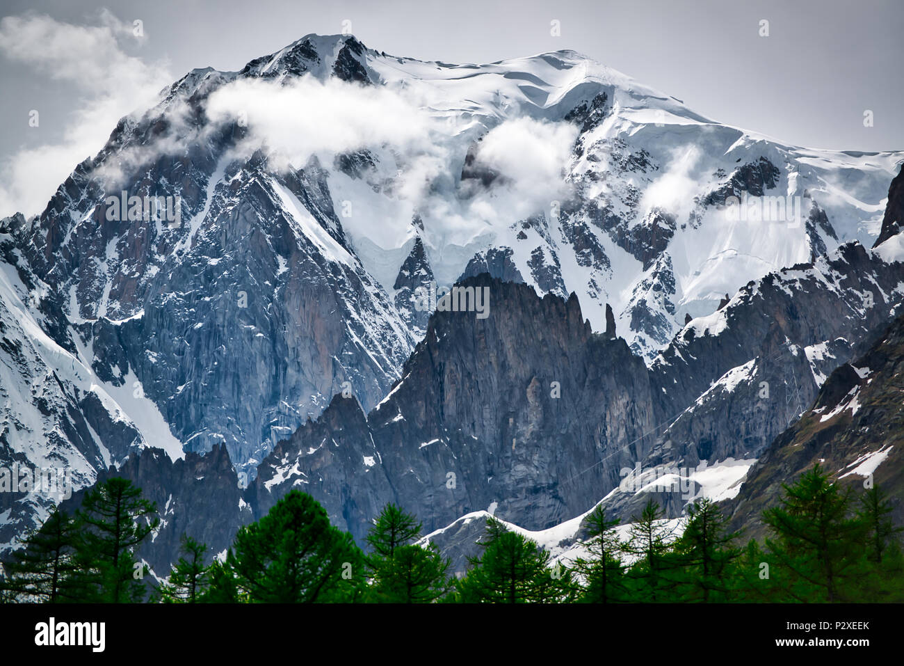Ghiacciaio di Mont Blanc visto dalla val Ferret in primavera con nuvole sul vertice e alberi in primo piano, Valle d'Aosta - Italia Foto Stock
