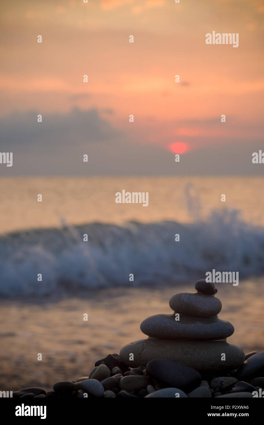 Piramide piegata Zen pietre ghiaia sul mare spiaggia al tramonto Foto Stock