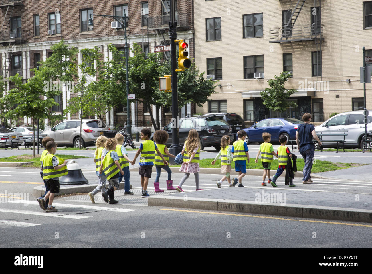 Gli insegnanti della scuola di piombo childrenacreoss Eastern Parkway nel Prospect Heights sezione di Brooklyn, New York. I bambini indossare speciali giubbotti iridescente che li rendono più visibili ai conducenti. Foto Stock