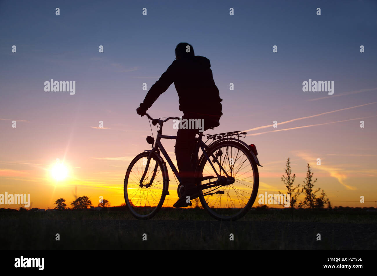 L'uomo corsa sulla bicicletta. Rider silhouette sulla bici retrò con Cielo di tramonto in background. Sana ricreazione e attività. Foto Stock
