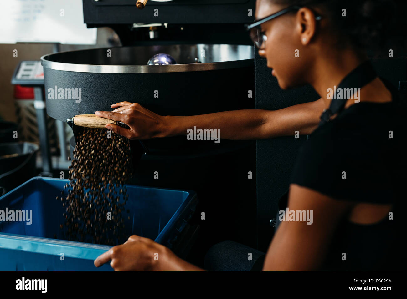 Barista femmina utilizzando caffè industriali macchina di torrefazione del caffè Foto Stock