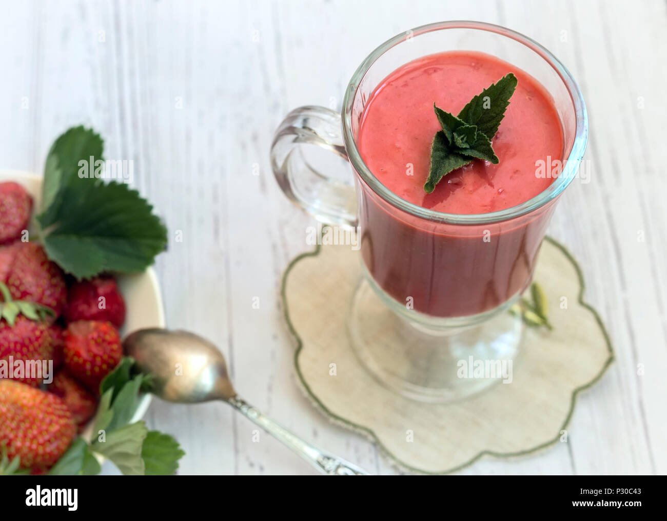 Sul tavolo su un tovagliolo un bicchiere di frullato di fragola, accanto a bacche Fragole. Foto Stock