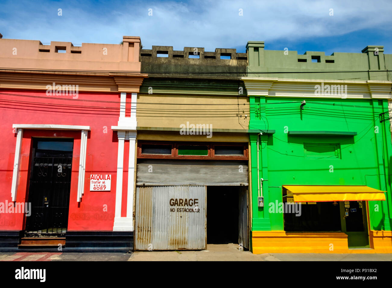 Case colorate stand nel centro della città di Carmelo, Uruguay. In mezzo, un garage grigio interrompe i colori forti. Foto Stock