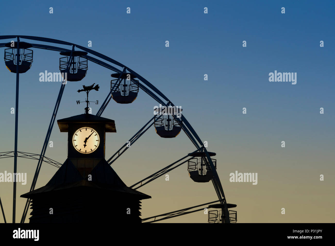 Il clock di Bournemouth Pier con la grande ruota in background sparato contro un cielo di sera. Foto Stock