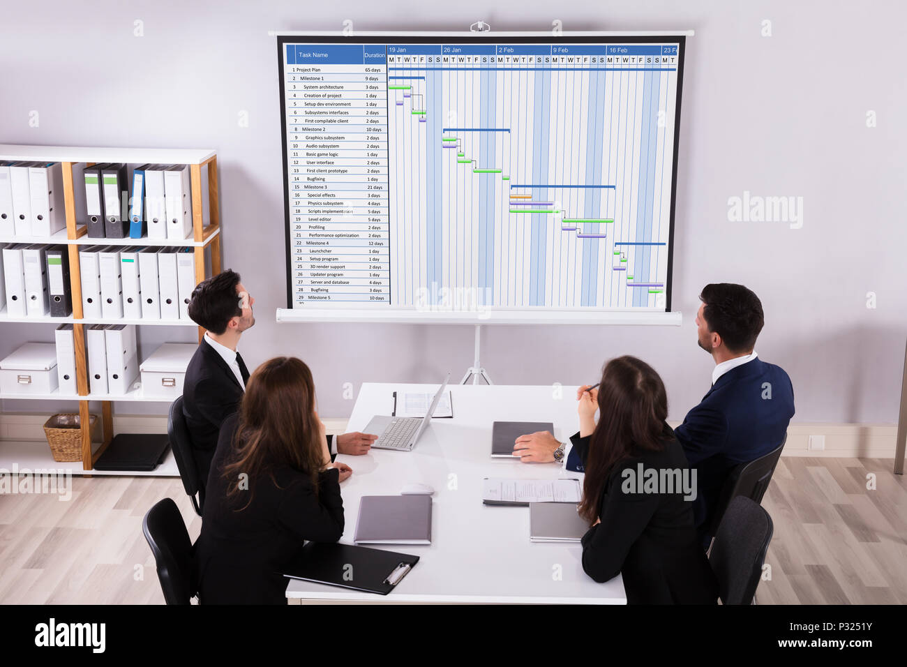 Gruppo di imprenditori analizzando diagramma di Gantt sul proiettore in ufficio Foto Stock