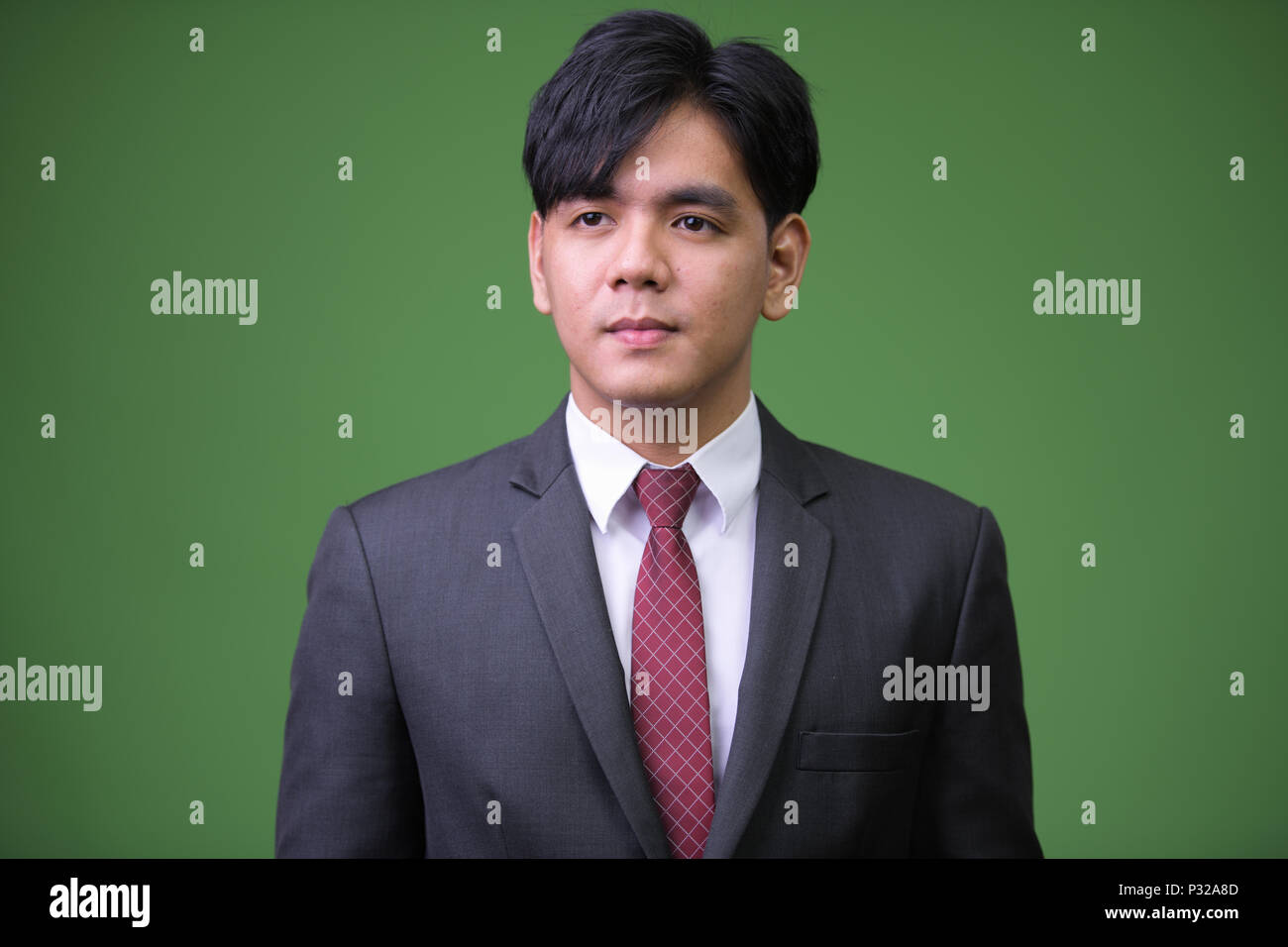 Bel giovane imprenditore asiatici contro lo sfondo di colore verde Foto Stock
