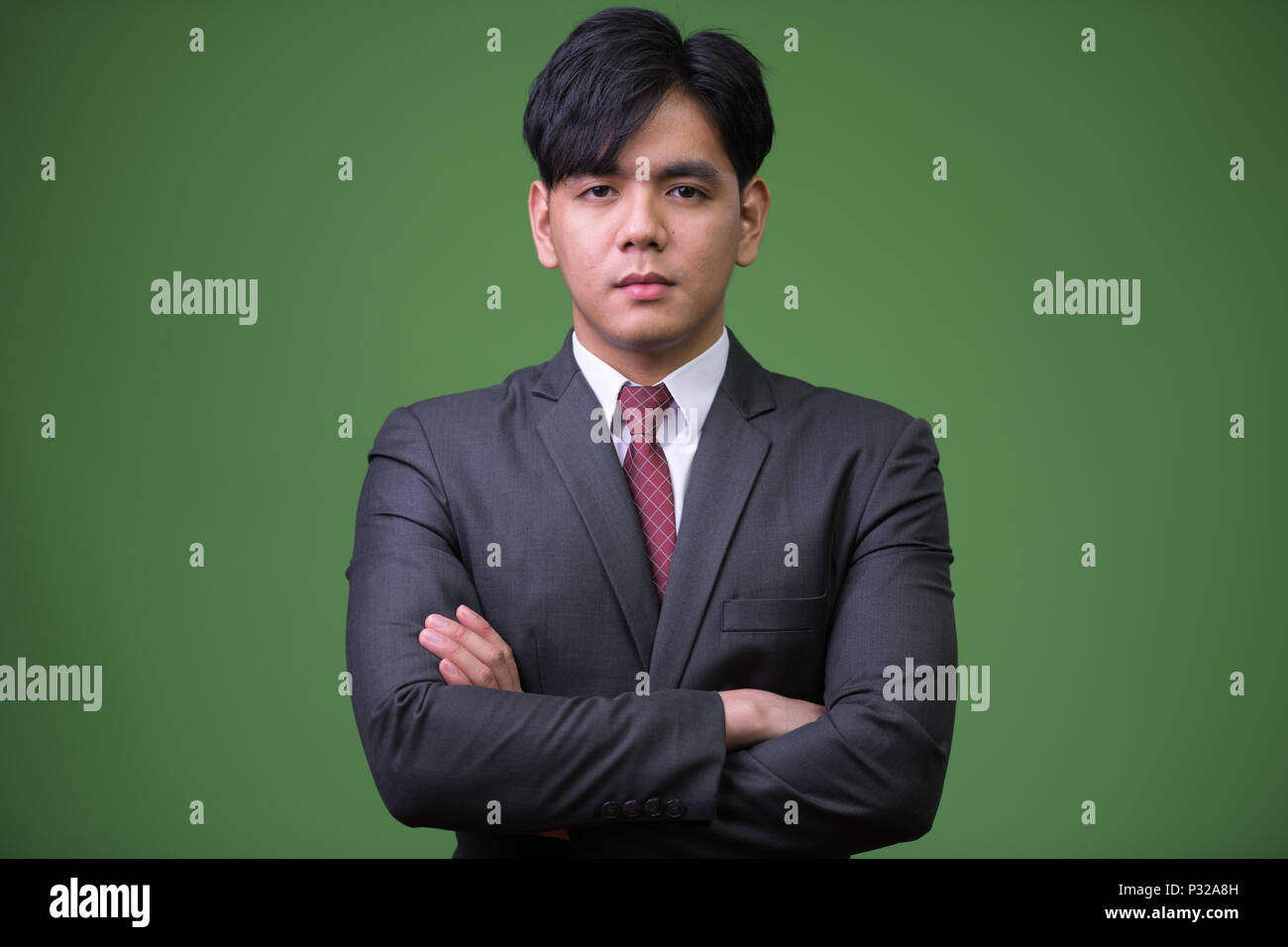 Bel giovane imprenditore asiatici contro lo sfondo di colore verde Foto Stock
