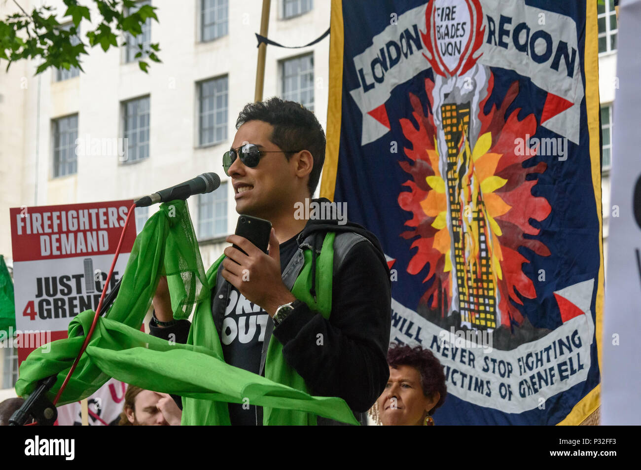 Londra, Regno Unito. Il 16 giugno 2018. Shabbir Lakha dell Assemblea Popolare parla alla protesta a Downing St in solidarietà con i 72 morti e i superstiti della Grenfell incendio di un anno fa ha organizzato dalla giustizia4Grenfell e il FBU (Vigili del Fuoco Unione). Dopo alcuni interventi hanno marciato per l'ufficio a casa per una breve protesta prima di ritornare a Downing St per ulteriori interventi. mm Credito: Peter Marshall / Alamy Live News Foto Stock