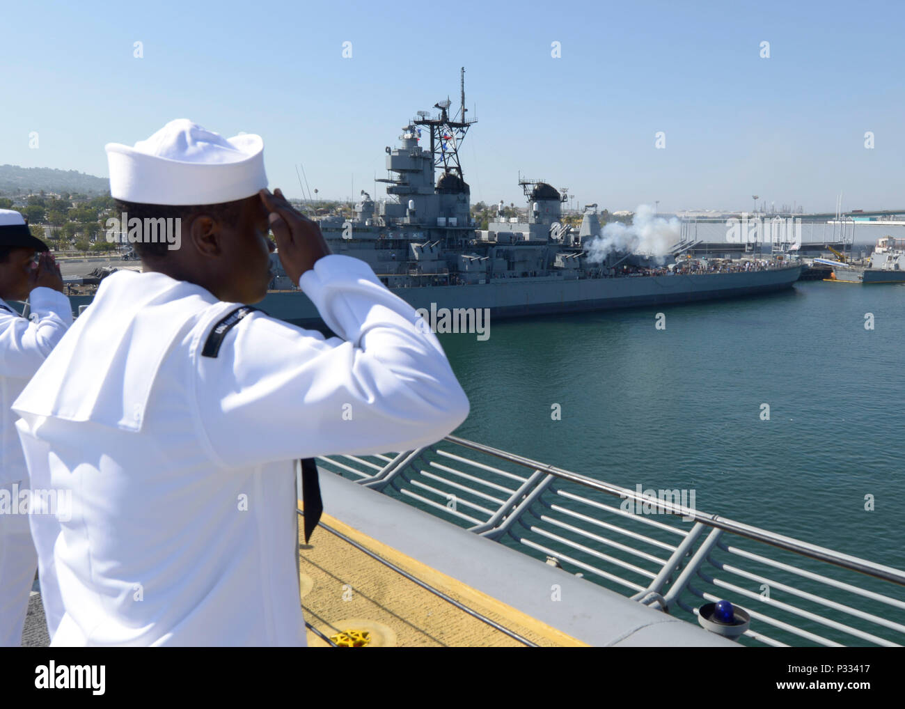 160830-N-OQ305-104 SAN PEDRO in California. (30 agosto 2016) un marinaio aboad USS America (LHA 6) rende un omaggio come La Corazzata Iowa Museum incendi i suoi 16 pollici/50-pistole di calibro in salute come la nave arriva a Los Angeles la settimana della flotta 2016.La cerimonia inaugurale di Los Angeles flotta settimana offre al pubblico la possibilità di tour navi, soddisfare i marinai, Marines e membri della Guardia Costiera e acquisire una migliore comprensione di come il mare servizi supporto la difesa nazionale degli Stati Uniti e la libertà dei mari. (U.S. Foto di Marina di Massa lo specialista di comunicazione 2a classe Robert R. SANCHEZ/rilasciato) Foto Stock