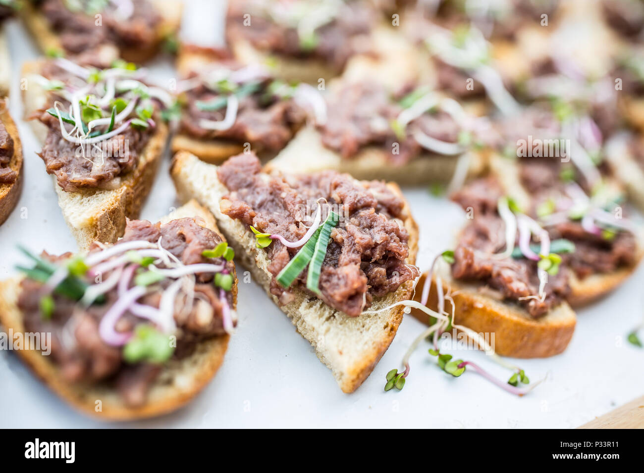 Carne di manzo crudo tartaro mini pane su una tavola di catering a caso. Foto Stock