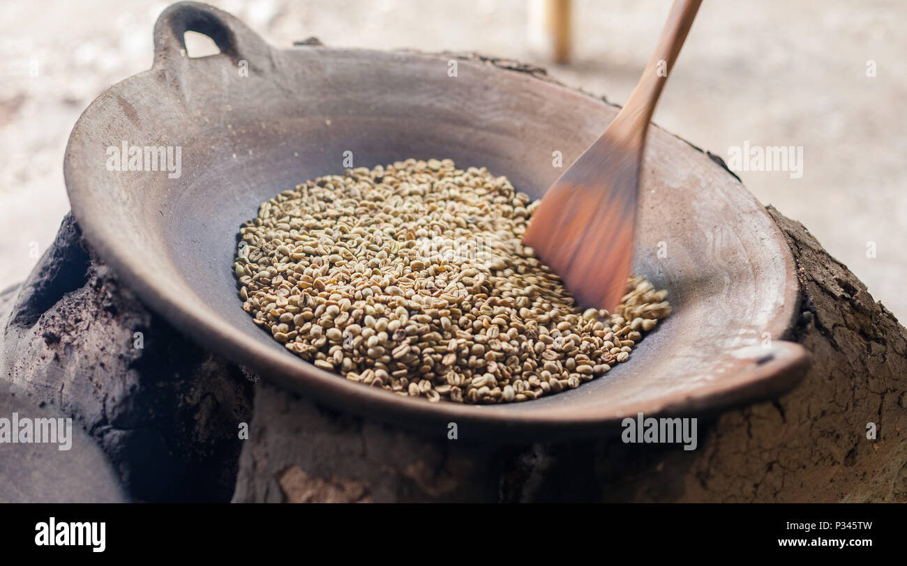 Master girarrosti arrosto manualmente i chicchi di caffè in un legno-sparò stufa vicino Banyuwangi, Java, Indonesia Foto Stock