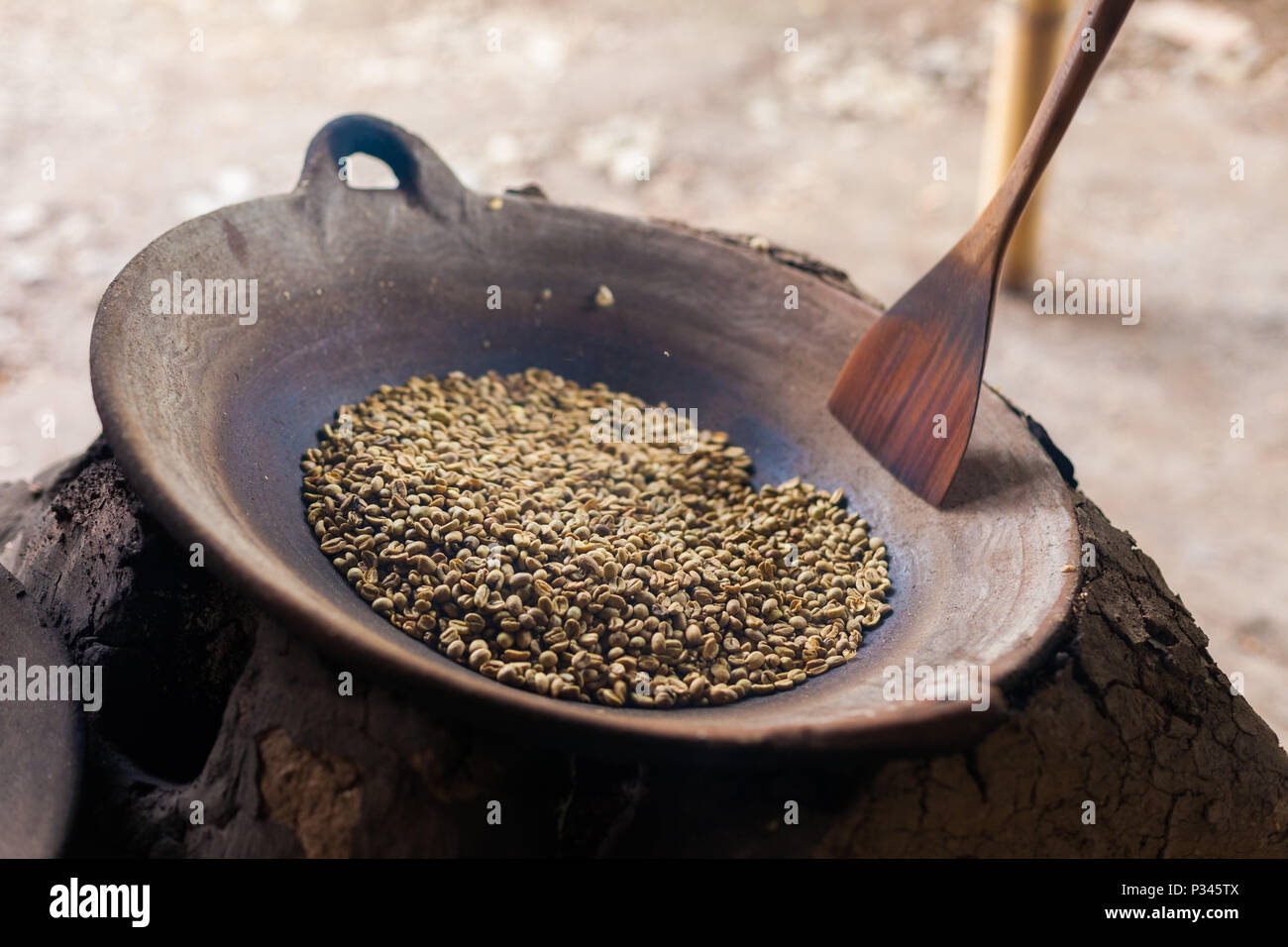 Master girarrosti arrosto manualmente i chicchi di caffè in un legno-sparò stufa vicino Banyuwangi, Java, Indonesia Foto Stock