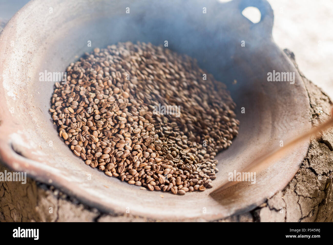 Master girarrosti arrosto manualmente i chicchi di caffè in un legno-sparò stufa vicino Banyuwangi, Java, Indonesia Foto Stock