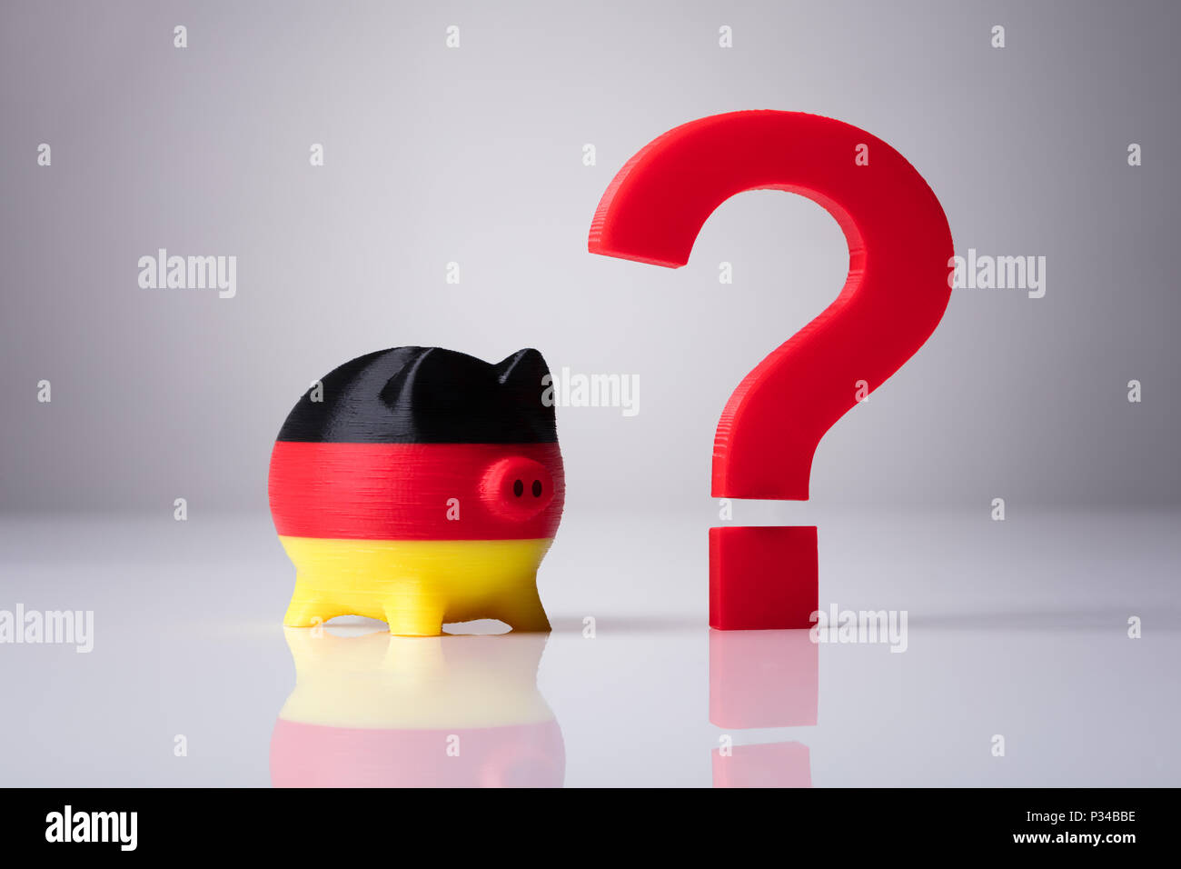 Close-up di Piggybank dipinta con bandiera tedesca e punto interrogativo rosso segno su sfondo riflettente Foto Stock