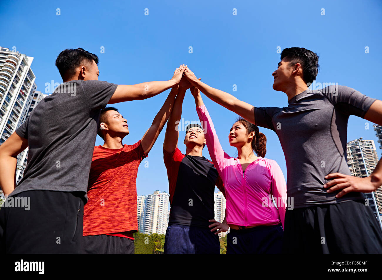 Team di asian adulti giovani sportivi e sportive mettendo le mani insieme a dimostrare unità e spirito di squadra. Foto Stock
