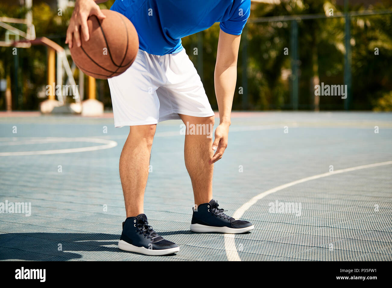 Giovane maschio asiatici giocatore di basket dribbling e praticare la sfera di abilità di manipolazione sulla corte. Foto Stock