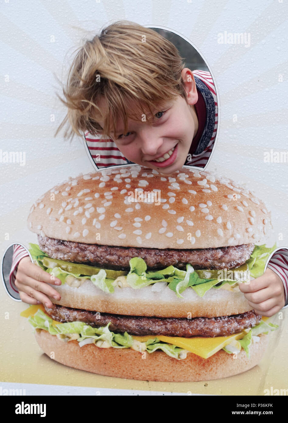 Utrecht, Paesi Bassi, ragazzo affiora la sua testa attraverso una parete di foto con l'immagine di un burger Foto Stock
