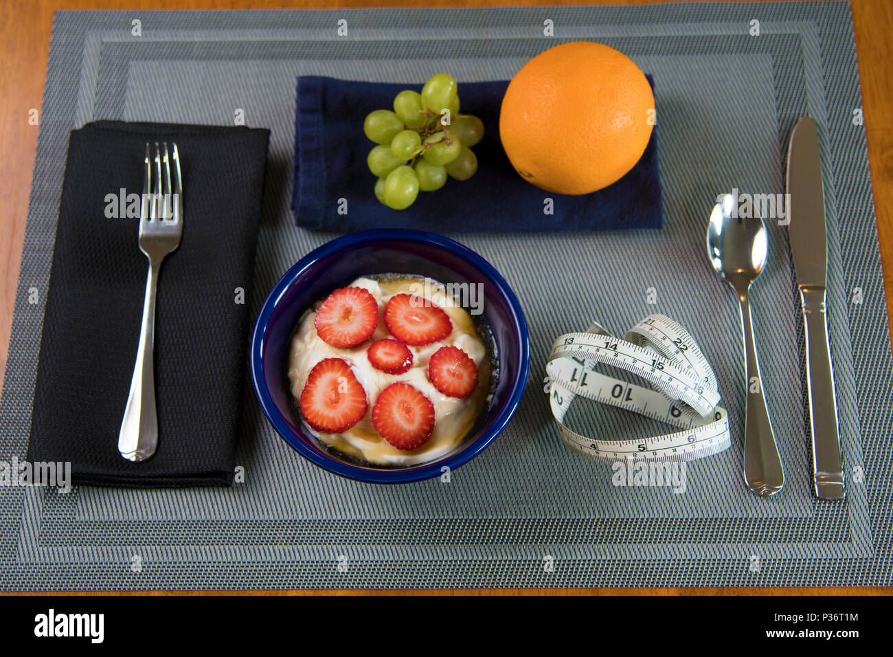 Cibo orizzontale colpo di uva, di un arancione e yoguhrt con fragole e miele e un metro a nastro. Foto Stock