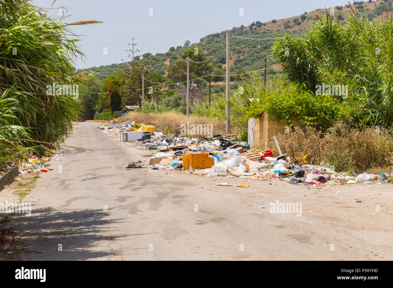 Rifiuti lungo una strada secondaria in un villaggio nel nord della Sicilia Foto Stock