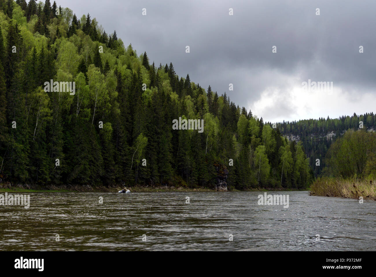 Paesaggio del fiume Ural Usva, il Chusovaya tributario, con pittoreschi boschiva costiera scogliere e una pesca barca gonfiabile in distanza, su un Foto Stock