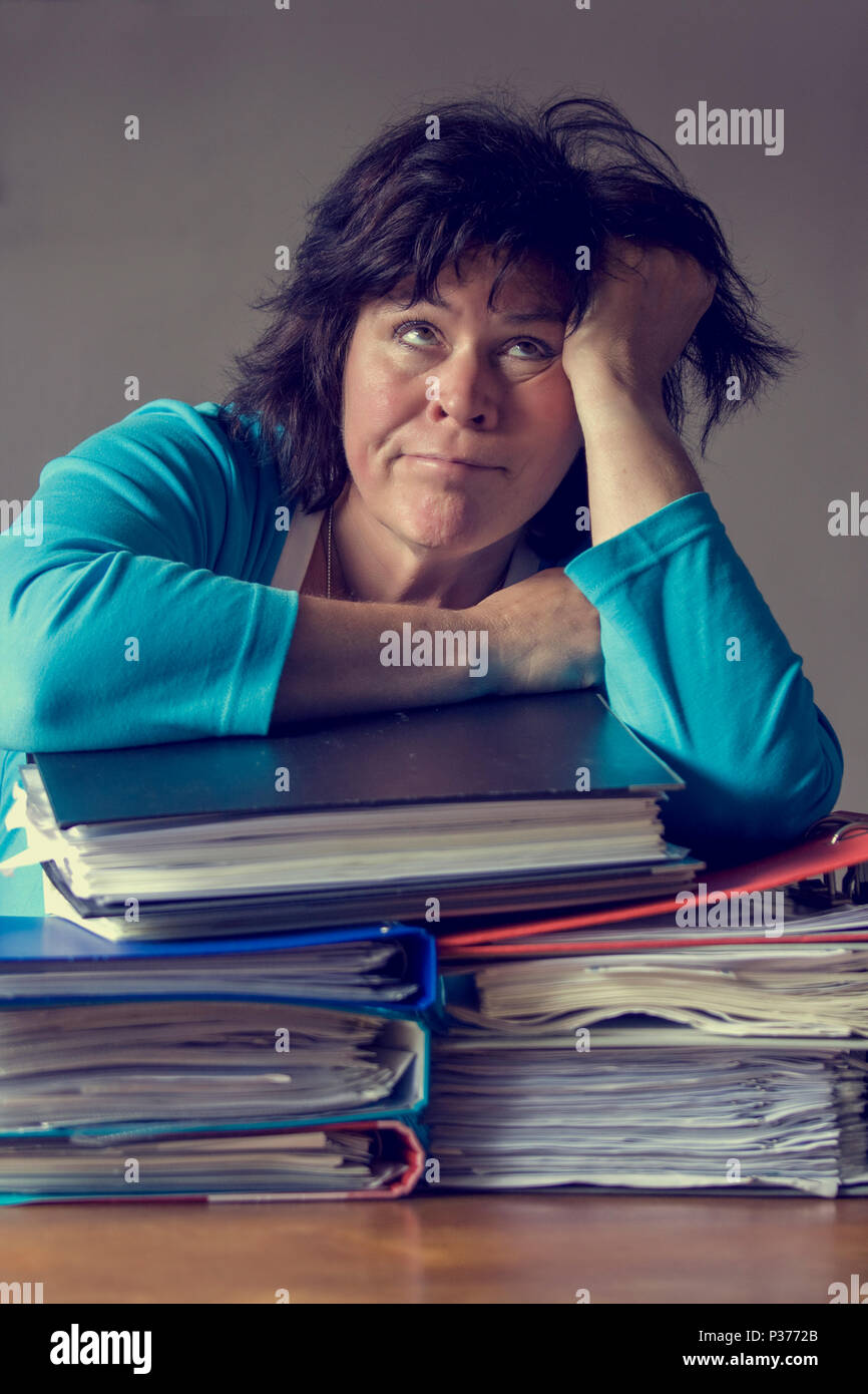 Donna anziana con bracci in appoggio sulla pila di file guardando verso l'alto Foto Stock