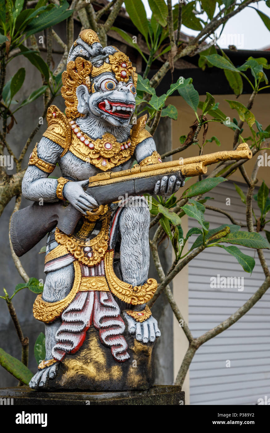 Statua di custode di un demone con un fucile vicino alla porta di casa. Badung, Bali, Indonesia. L'immagine verticale. Foto Stock