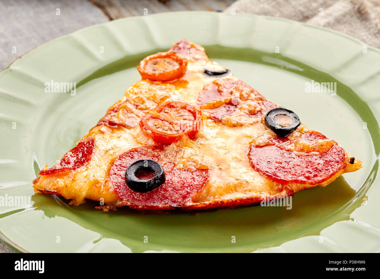 Fetta di salsiccia per pizza pizza sul piatto verde Foto Stock