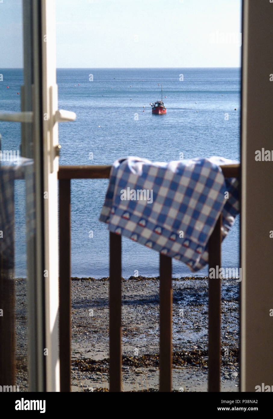 Controllare blu panno sulla rampa con balcone con vista della barca al di ancoraggio sul mare Foto Stock