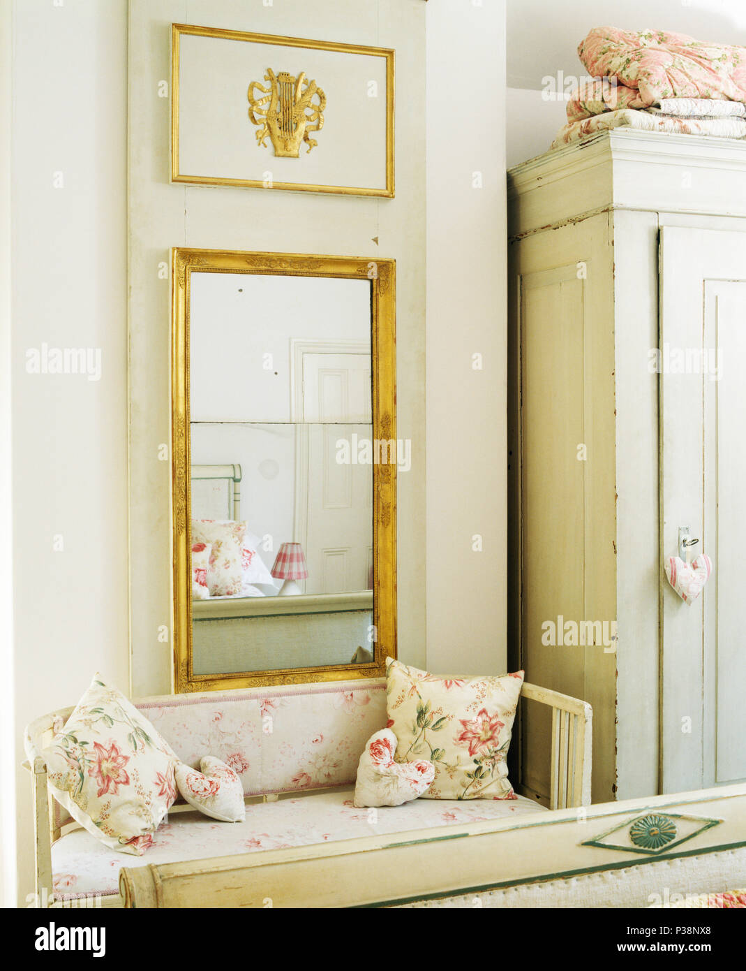 Rettangolare specchio dorato sopra dipinto di stabilirsi con rose cuscini  modellato in bianco paese camera da letto Foto stock - Alamy