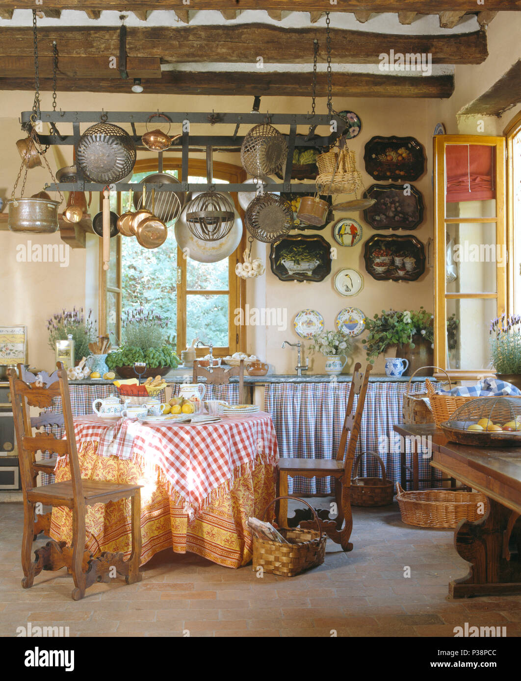 Controllare rosso panno sul tavolo con scaletta-back sedie in stile rustico toscano sala da pranzo con pentole sul soffitto rack Foto Stock