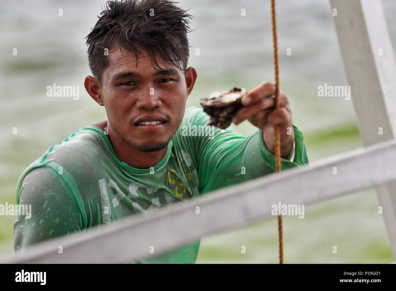 Alloggiamenti per North Bay, Philippines-October 15, 2016: pescatore filippino nella sua barca di legno si avvicina un turista bangka offrendo la sua cattura di ostriche alla v Foto Stock
